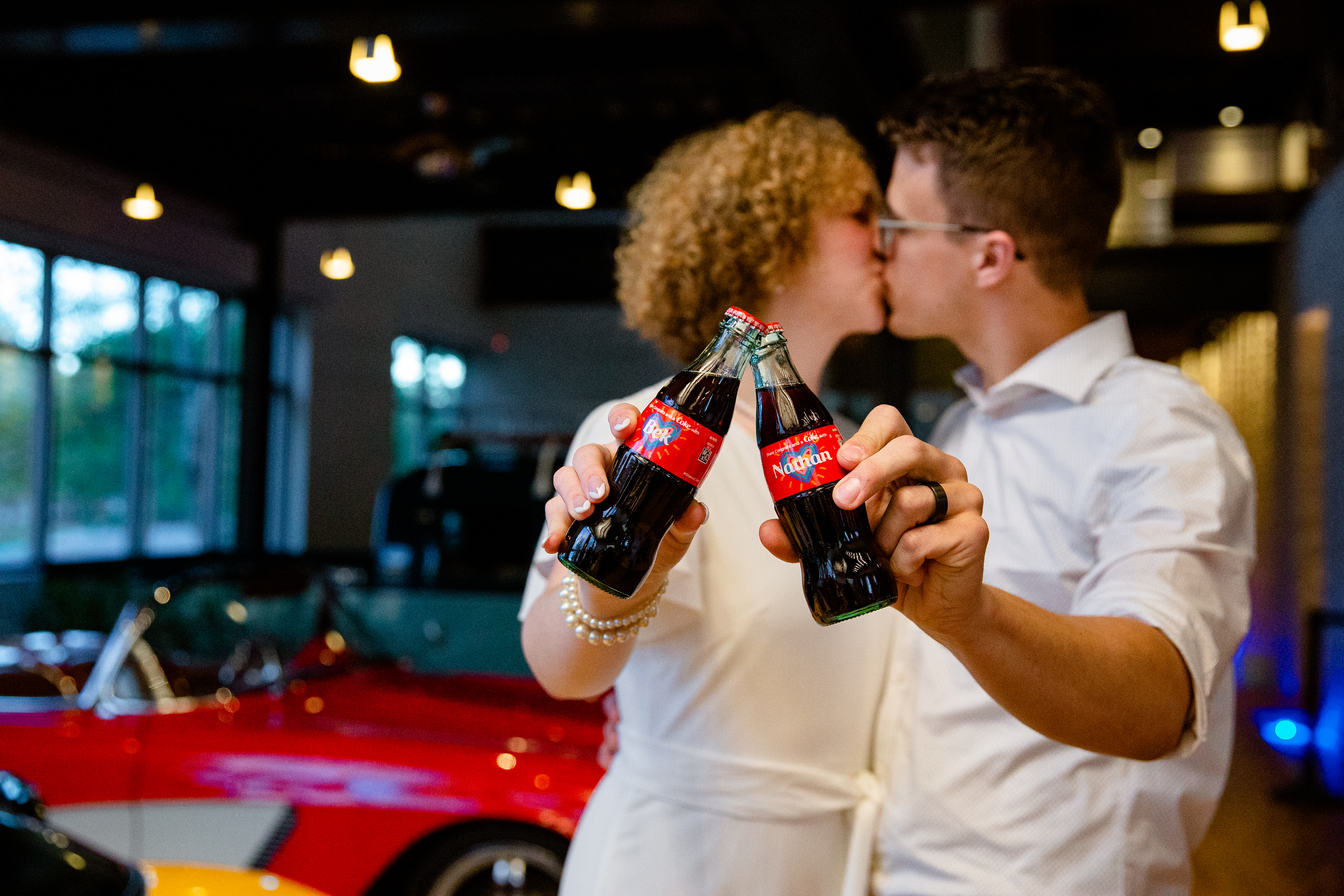 A photo of Nathan and Bek in the background with custom Coca-Cola bottles in the foreground with their names.